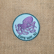 Blue iron-on patch with a graphic of a purple octopus and the words "Cape May, NJ" underneath it.