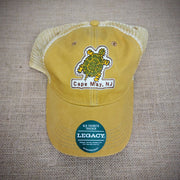 Mustard colored trucker hat with a khaki mesh and snap back closure. Patch of a turtle is on the front with Cape May, NJ underneath it.