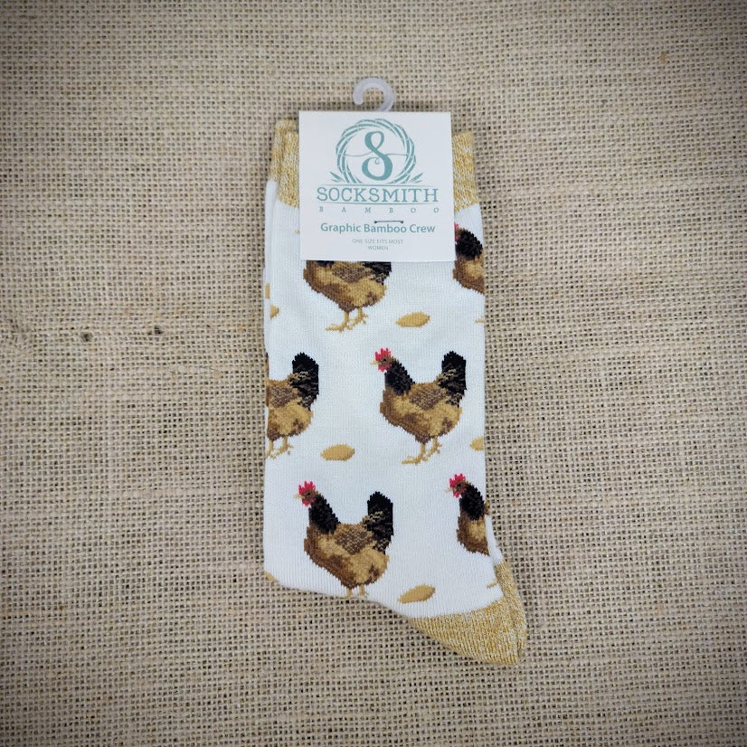 An ivory and mustard pair of socks with hens and eggs on it.