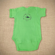 A green baby onesie featuring a cartoon flying fish. The text "THE FLYING FISH STUDIO, WEST CAPE MAY NJ" is printed around &  below the design.
