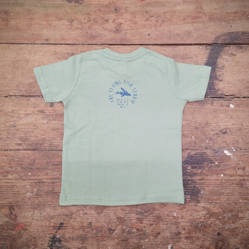 A light green t-shirt featuring the Flying Fish Studio logo on the back neck in navy ink.
