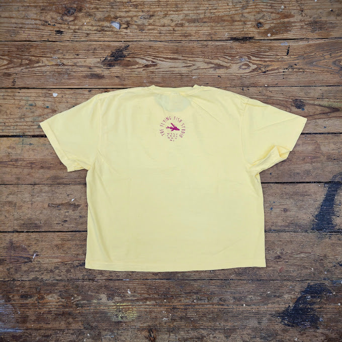 Cropped, buttery-yellow t-shirt with the "Flying Fish" logo on the back neck.