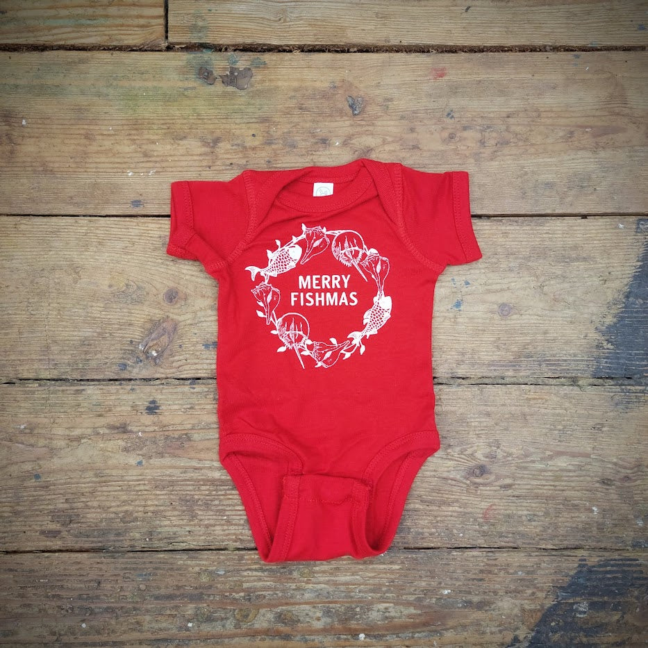 A baby onesie in red depicting "Merry Fishmas" on the front in white ink.
