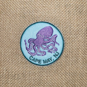 Blue iron-on patch with a graphic of a purple octopus and the words "Cape May, NJ" underneath it. 