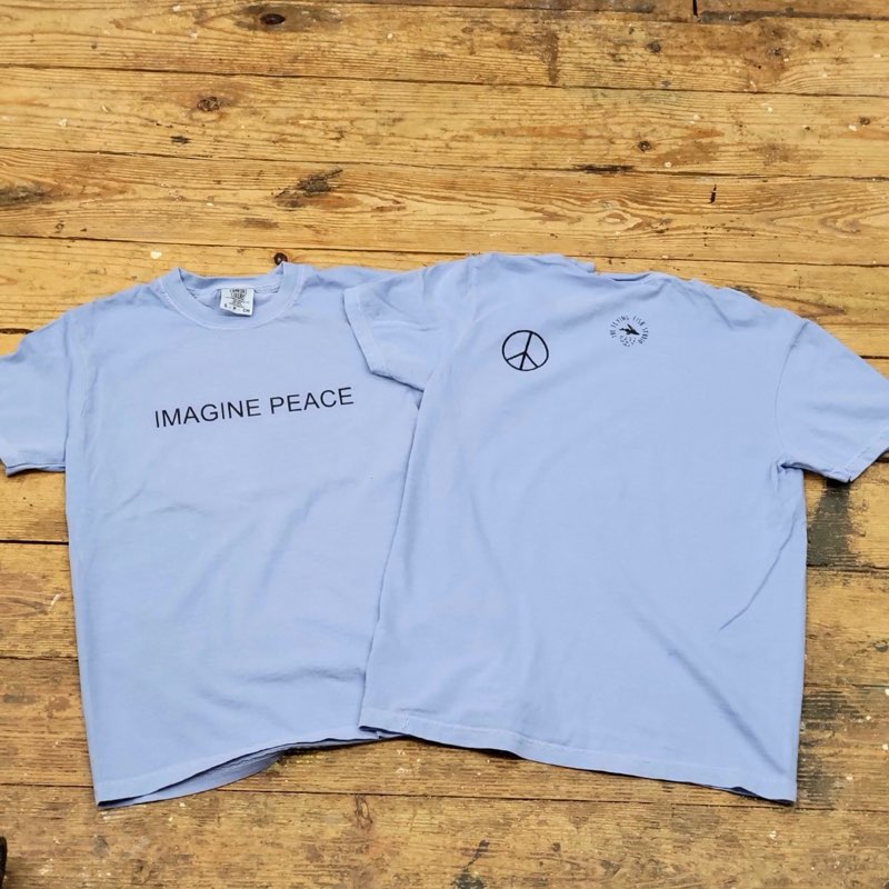 Two blue t-shirts with text on them that says, "IMAGINE PEACE."