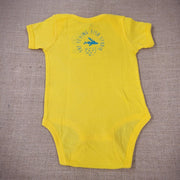 A bright yellow baby onesie featuring a cartoon flying fish. The text "THE FLYING FISH STUDIO, WEST CAPE MAY NJ" is printed below the design.