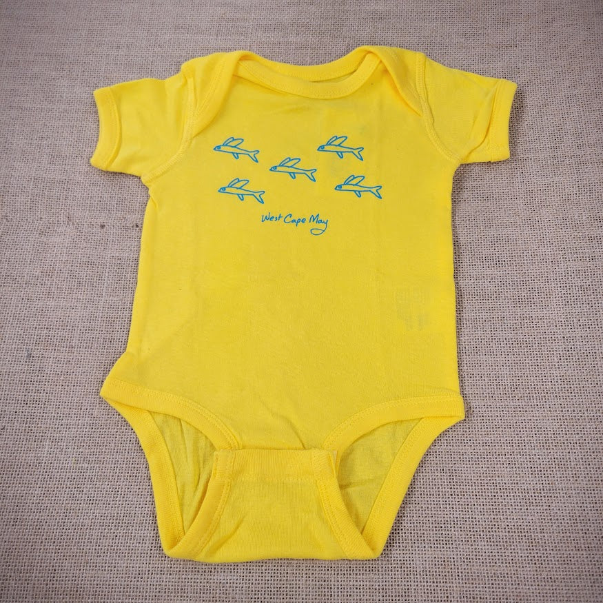 A bright yellow baby onesie with a graphic of cartoon flying fish.