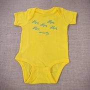 A bright yellow baby onesie with a graphic of cartoon flying fish.