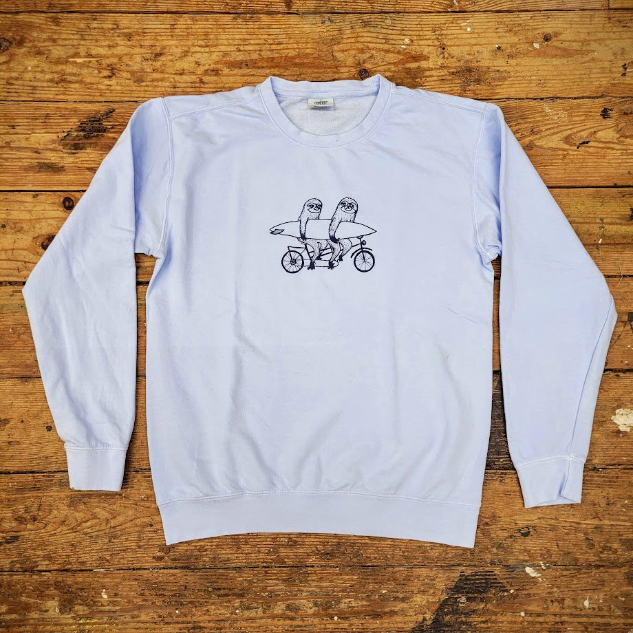 A blue crewneck sweatshirt with a graphic of two sloths on a tandem on the front.