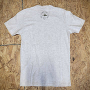 Grey, heathered T-shirt laid flat on a wooden background with the 'Flying Fish Studio' logo on the back of the neck in green ink.