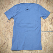 The back of a blue T-shirt laid flat on a wooden surface with the 'Flying Fish Studio' logo screen-printed on the back of the neck in black ink.