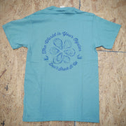 Greenish-blue T-shirt with a graphic design of oysters and text that says 'THE WORLD IS YOUR OYSTER! DON'T SHUCK IT UP!' on a wooden surface.