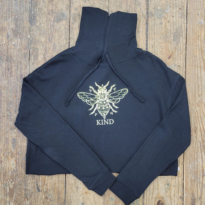 Solid Black, cropped pull-over hoodie featuring the 'Bee Kind' design on the center front in a cream ink.