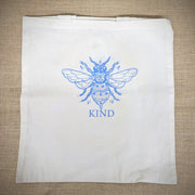 Natural, canvas tote bag with 'Bee Kind' design on the front in blue.