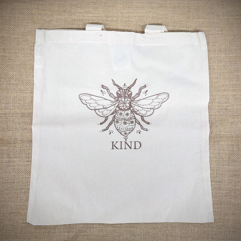 Natural, canvas tote bag with 'Bee Kind' design on the front in brown.