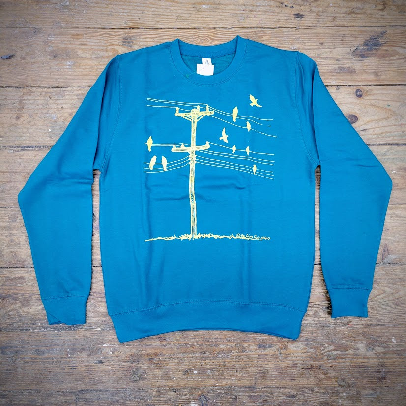 A blue sweatshirt with the 'Birds on a Wire' design on the front in butter yellow ink.