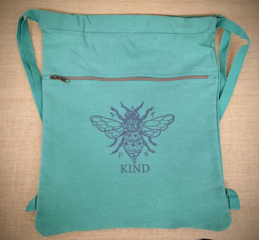 A seafoam blue drawstring bag with a blue 'Bee Kind' design on the front.