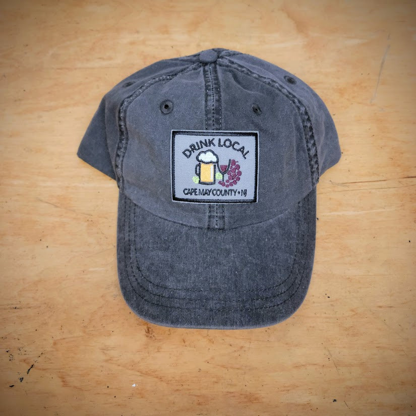 A solid black, classic hat with a 'Drink Local' patch on the front.