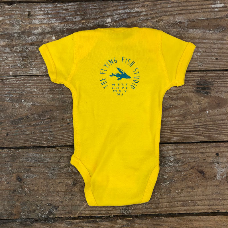 Bright yellow onesie featuring the 'Flying Fish' logo on the upper back in blue ink.