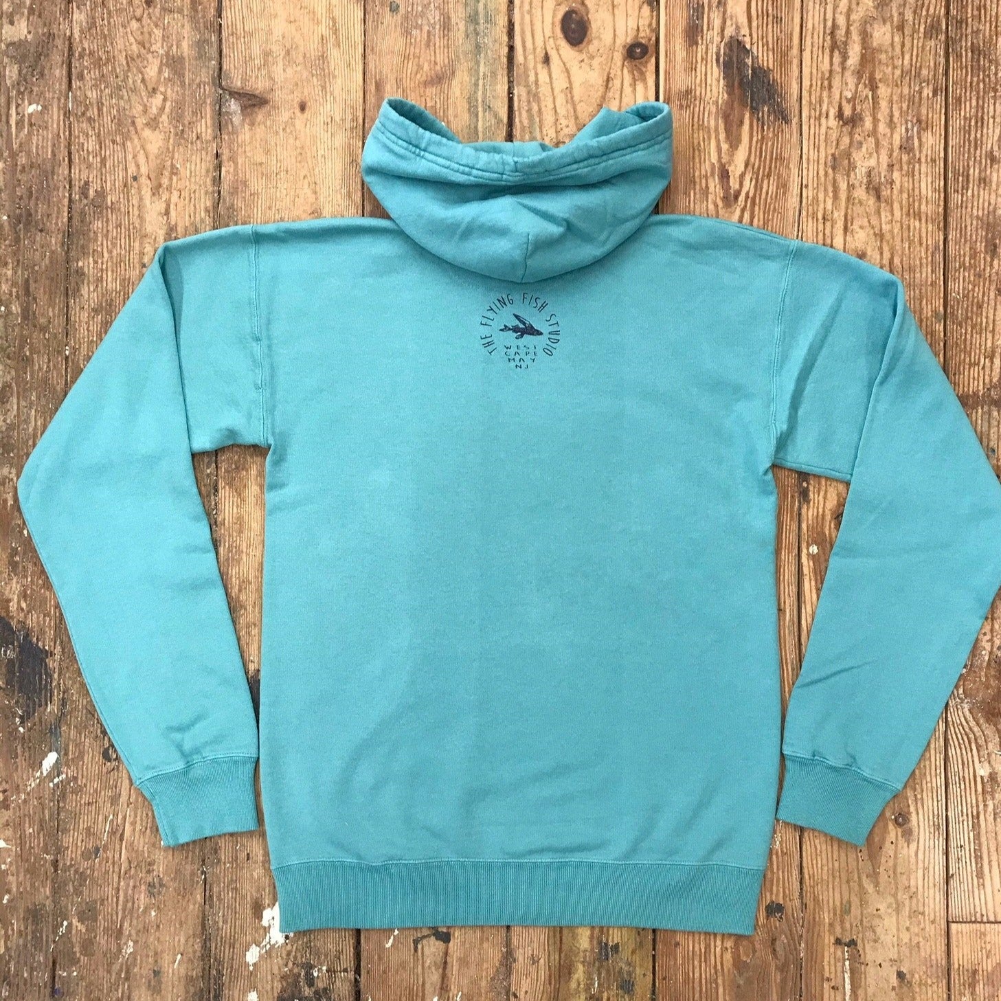 Seafoam Green hoodie featuring the 'Flying Fish' logo on the back neck in navy ink.