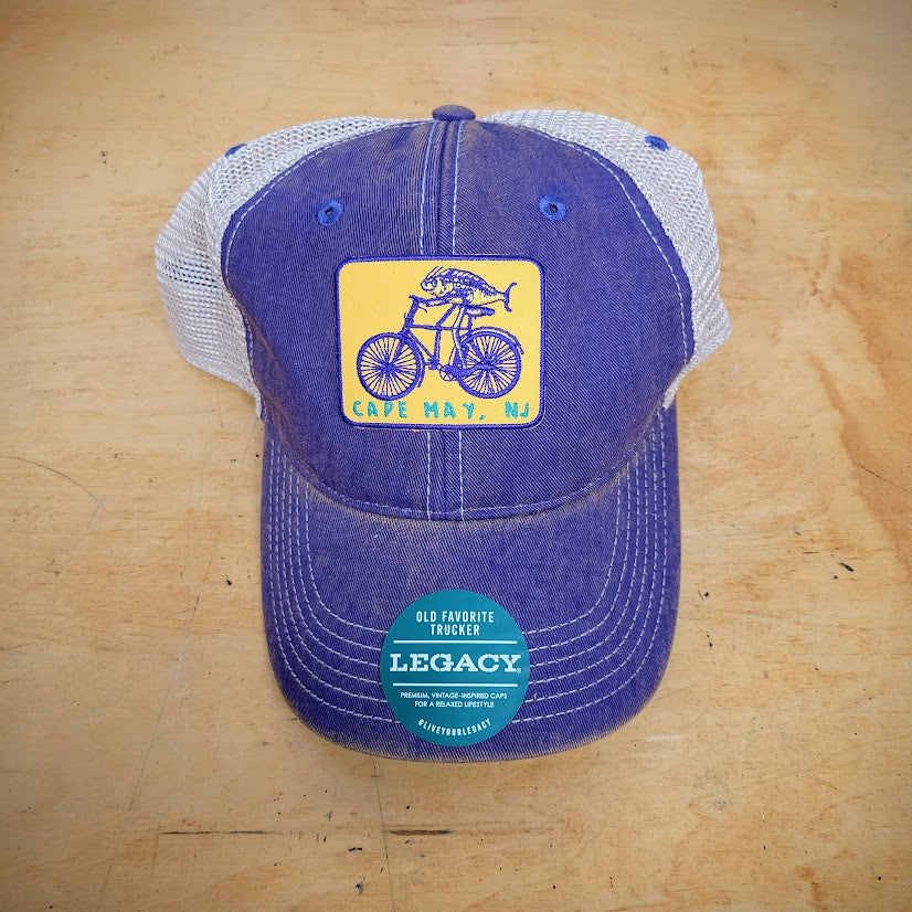 A purple-khaki trucker hat with the 'Fish on a Bike' patch on the front.