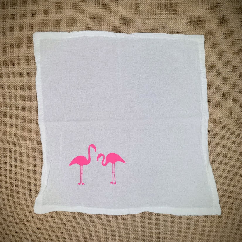 Flour sack napkin featuring the 'Lynn's Flamingos' design on the bottom left in hot pink ink.