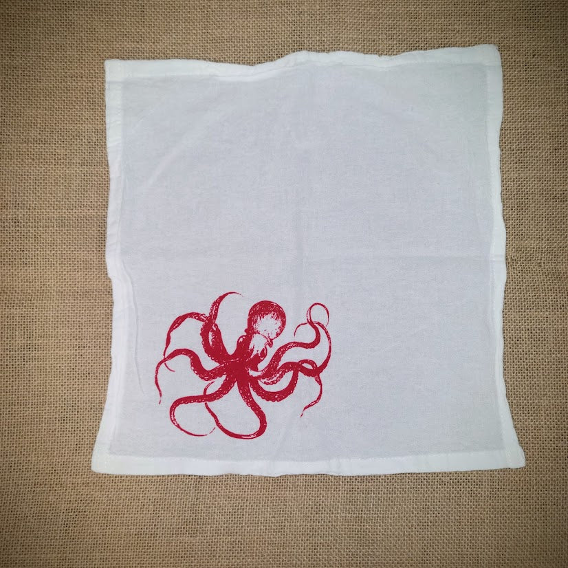 Flour sack napkin featuring the red 'Octopus' design on the bottom left.