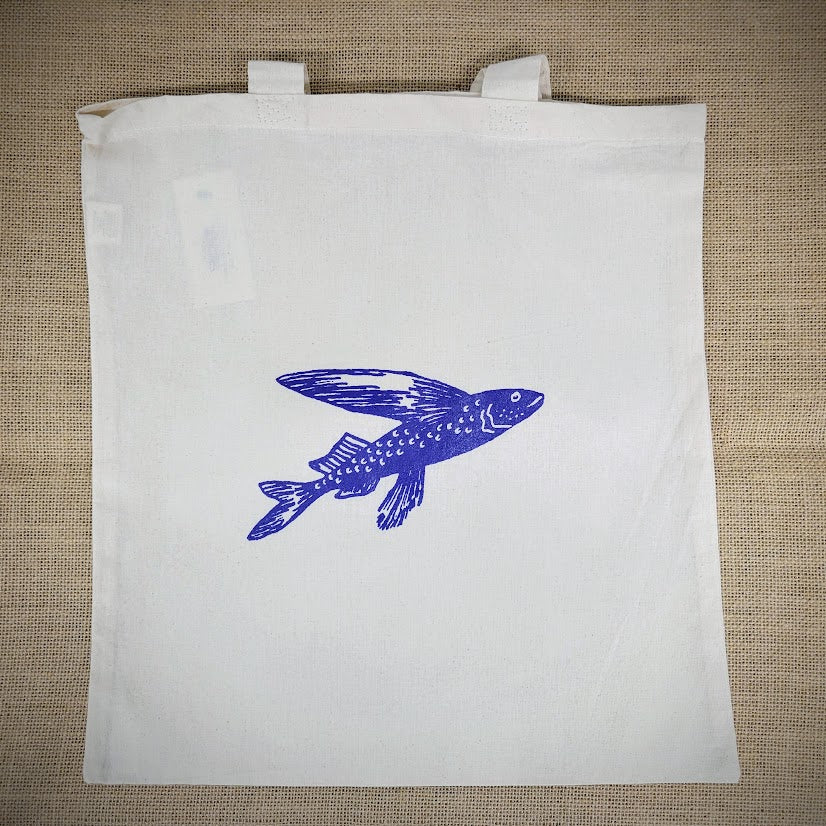 Natural, canvas tote bag with a blue flying fish design on the front.