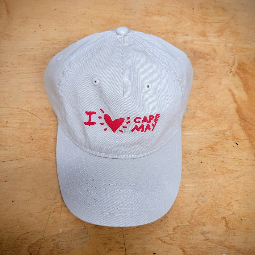 A khaki, classic hat with 'I (heart) Cape May' on the front in red ink.