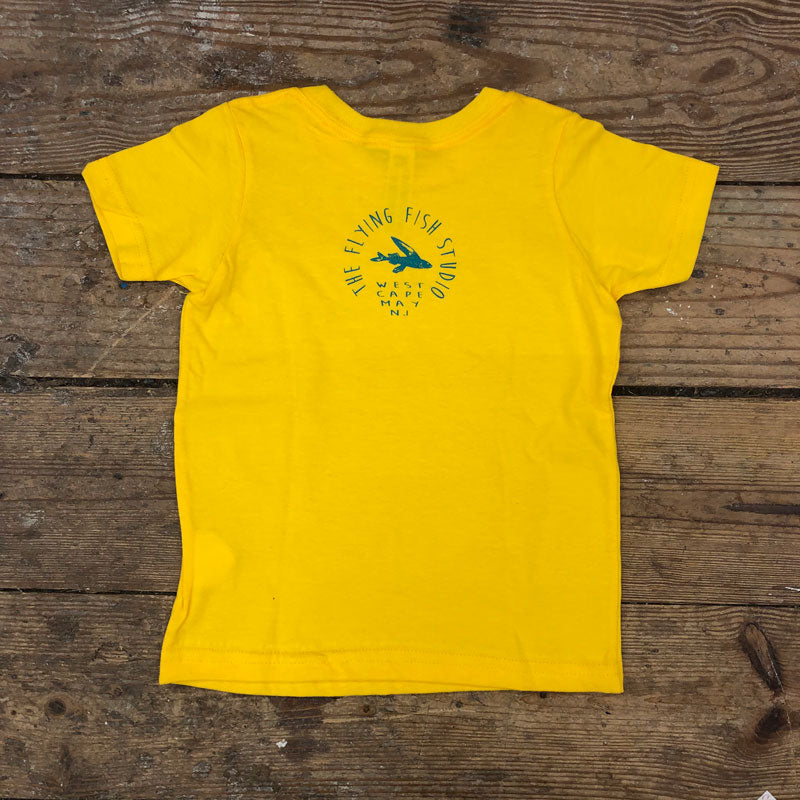 A yellow t-shirt featuring the 'Flying Fish Studio' logo on the back neck in blue ink.