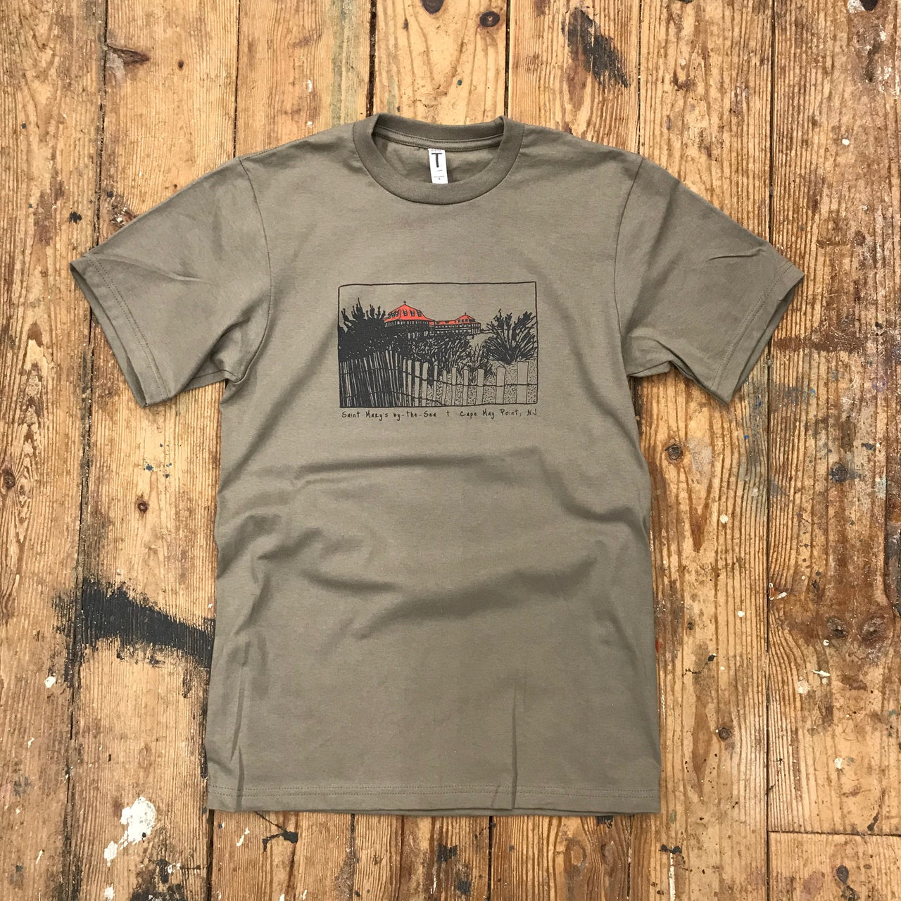 A warm grey t-shirt featuring the 'Saint Mary's by The Sea' design on the front in red and black ink.