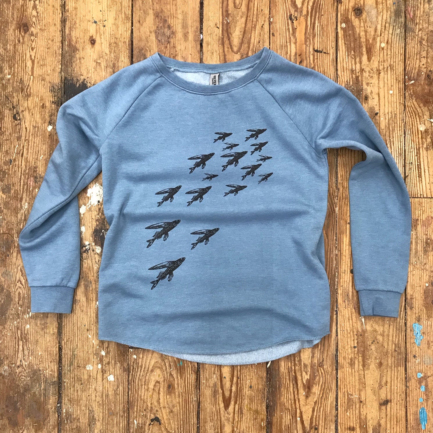 Misty blue sweatshirt featuring the 'School of Fish' design in black ink.