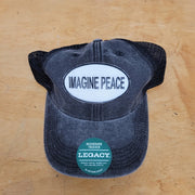 A grey-black trucker hat with an 'Imagine Peace' patch on the front.