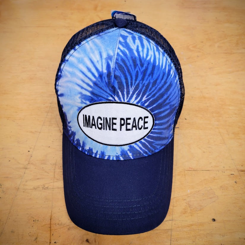 A blue tie-dye trucker hat with an 'Imagine Peace' patch on it.