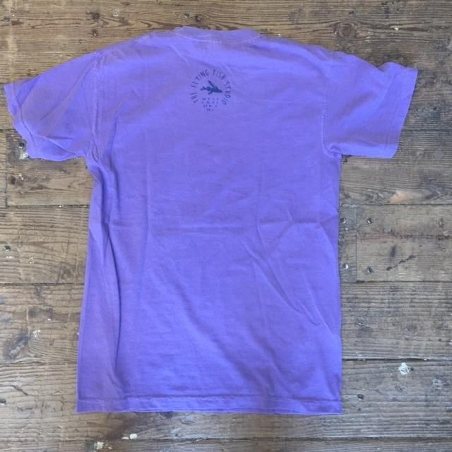 A purple t-shirt with the 'Flying Fish Studio' logo on the back neck in dark purple ink.