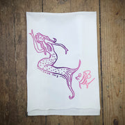 White, flour sack tea towel featuring the 'Mermaid, Cape May' design in a purple and pink gradient ink.