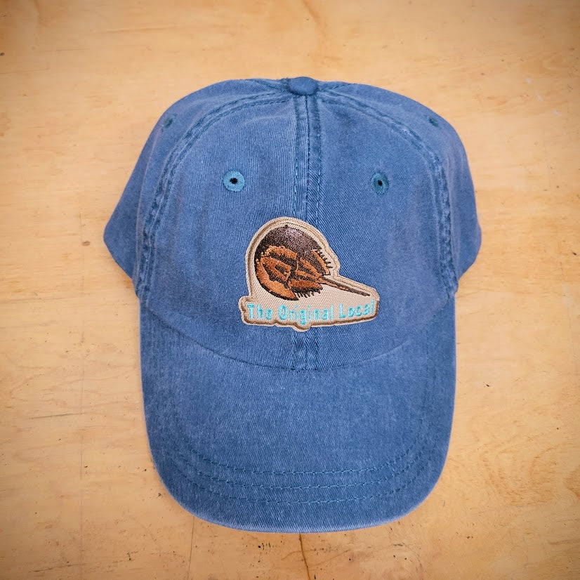 A blue, classic hat with a 'Horseshoe Crab' patch on the front.