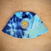 A blue and purple tie-dye bucket hat with a 'West Cape May' patch on it.