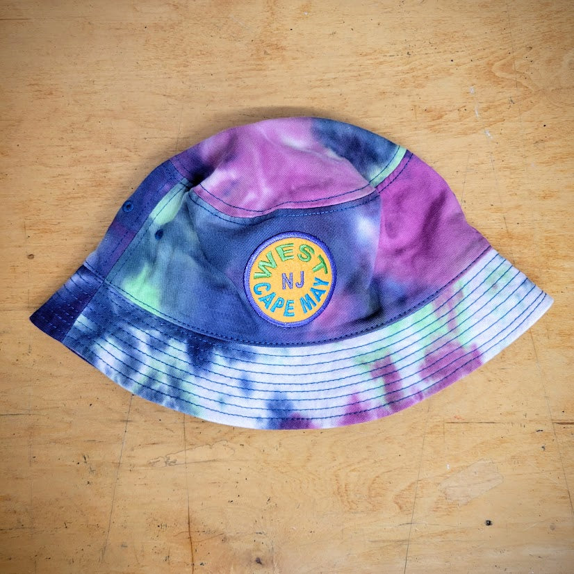 A purple and green tie-dye bucket hat with a 'West Cape May' patch on it.