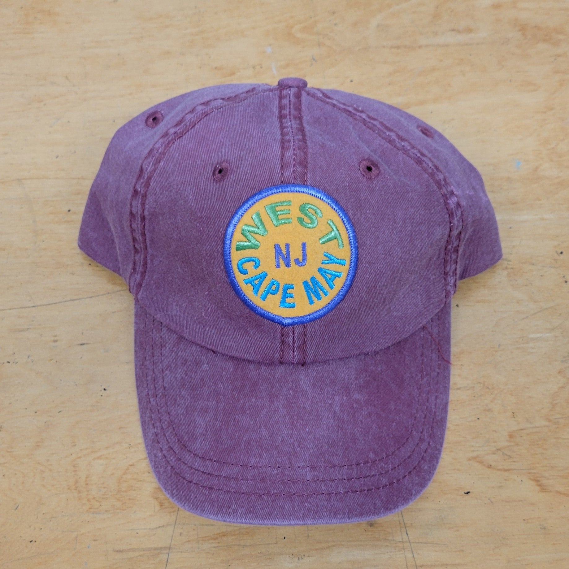A wine-purple, classic hat with a 'West Cape May' patch on it.