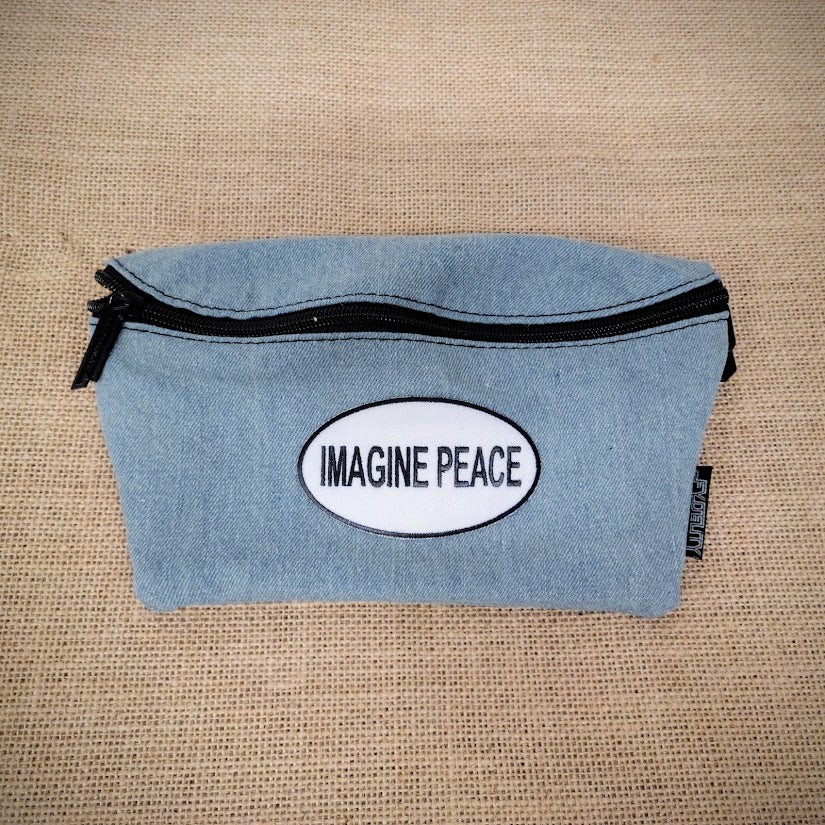 A denim blue fanny pack with an Imagine Peace patch on it.