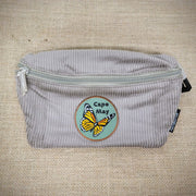 A khaki fanny pack with a monarch butterfly patch on it.