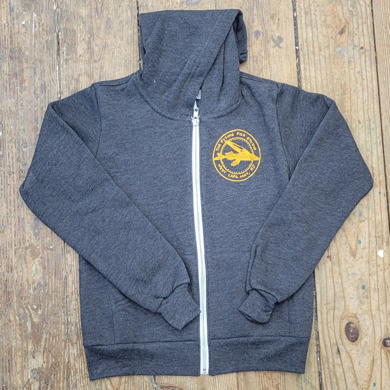 Heather, Dark Grey zip-up jacket featuring the 'Flying Fish' logo design on the left chest in soft orange ink.