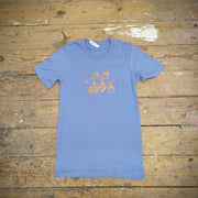 A periwinkle t-shirt with 'Sloths on a Tandem' design on the front in orange ink.