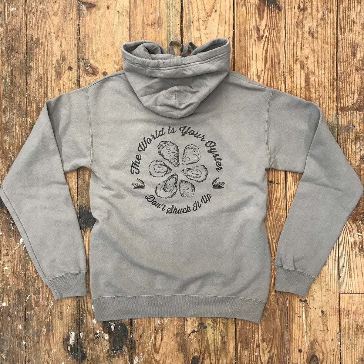 Warm Grey hoodie featuring the 'The World is Your Oyster, Don't Shuck it Up' design on the back in black ink.