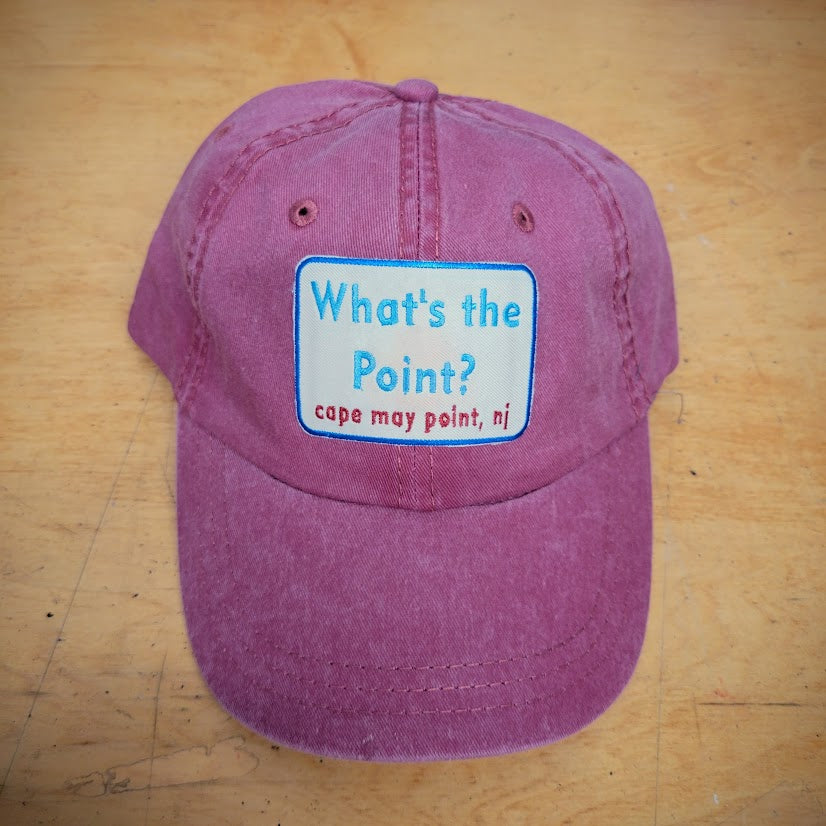 A red, classic hat with a 'What's the Point?' patch on the front.