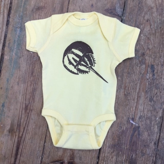 Pastel yellow onesie featuring a brown 'horseshoe crab' design on the front.