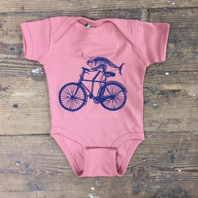 Mauve onesie featuring a 'Fish on a Bike' design on the front in navy ink. 
